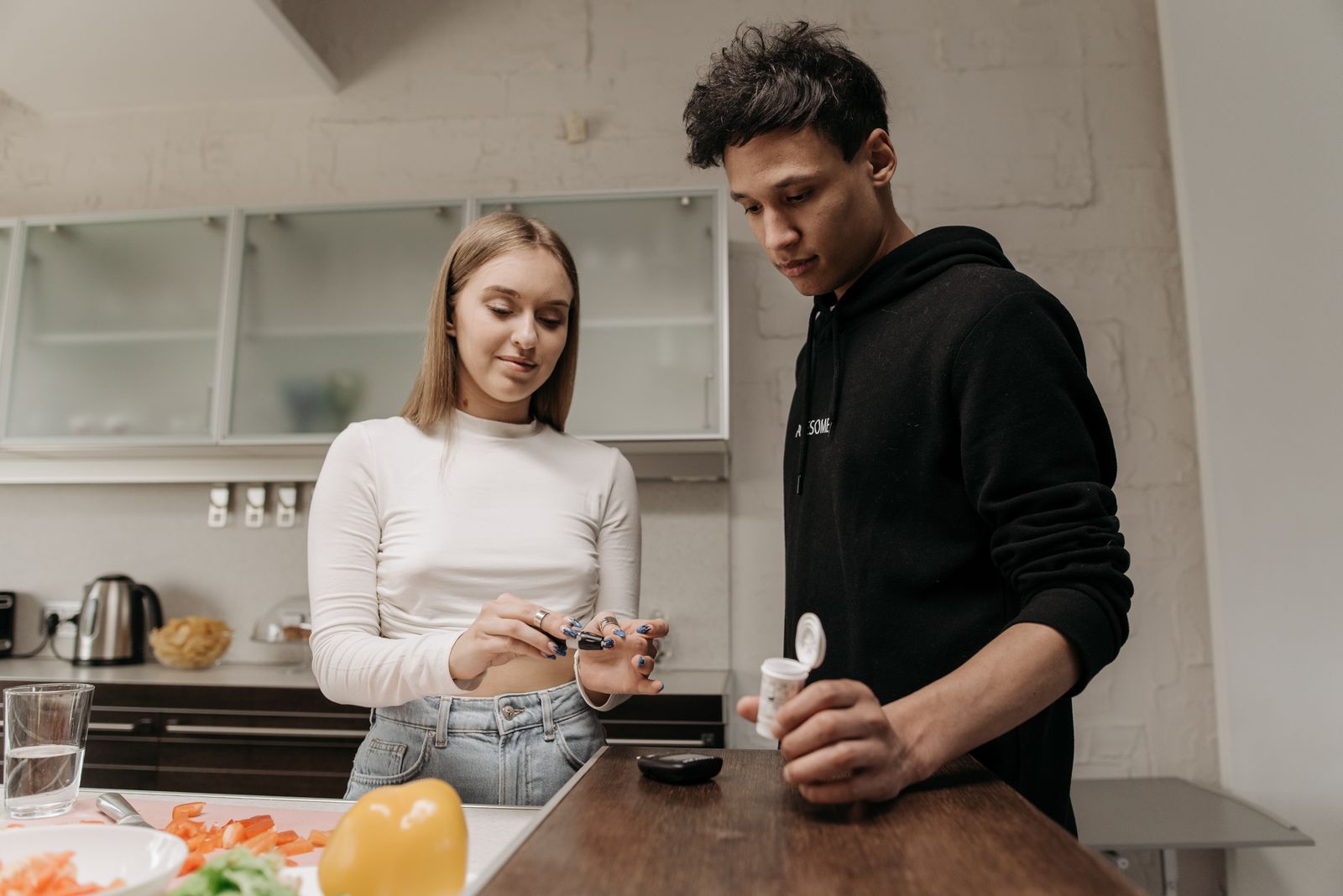 Two adults checking blood glucose at home